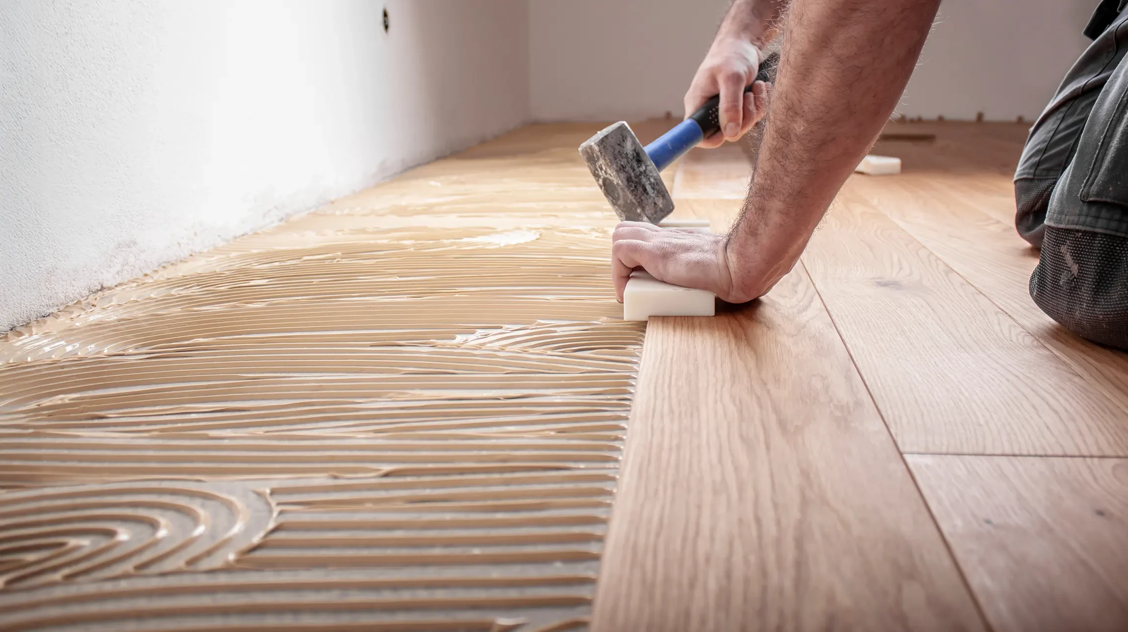 Plancher en bois clair avec planches horizontales disposées en rangées parallèles. Surface en bois naturel blanchi ou délavé présentant des nœuds caractéristiques et veines du bois apparentes. Texture lisse avec finition mate. Assemblage à joints droits entre les lames. Essence probable pin ou sapin traité, aspect vieilli ou patiné blanc cassé.